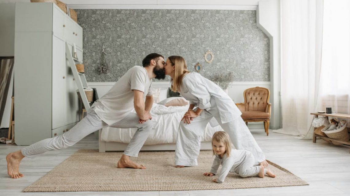 A family enjoying playful bonding moments in a stylish, minimalistic bedroom setting.
