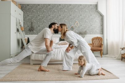 A family enjoying playful bonding moments in a stylish, minimalistic bedroom setting.