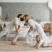 A family enjoying playful bonding moments in a stylish, minimalistic bedroom setting.