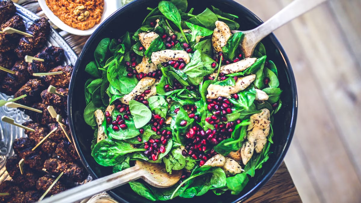 Healthy and vibrant spinach salad with grilled chicken and pomegranate seeds, perfect for a nutritious meal.